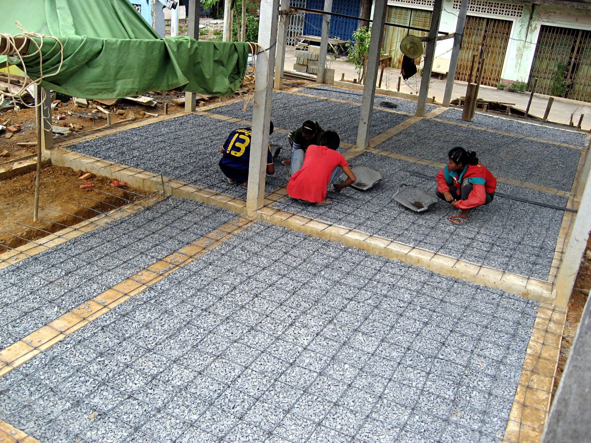 Workers tying a rebar mesh for a concrete floor slab.